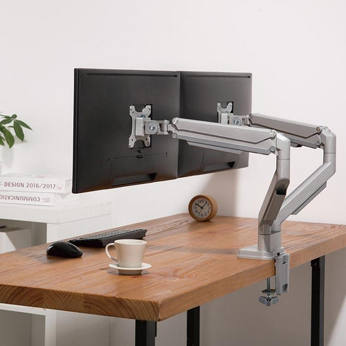 The Echo Dual Monitor Arm, shown in silver, mounted to a butcher block desktop. Rear angle view.