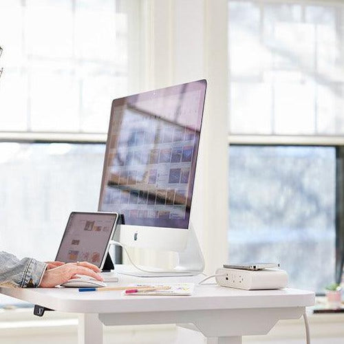 White Ellipse Qi wireless power block on a desk, featuring AC outlets, USB ports, and a charging pad.